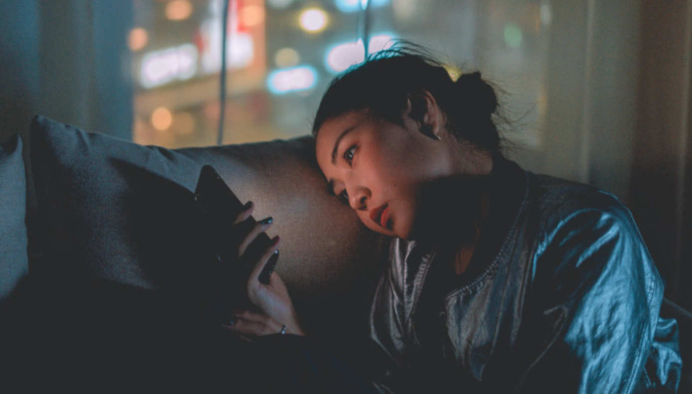 Woman stares at mobile phone in her hand longing hoping for a text back